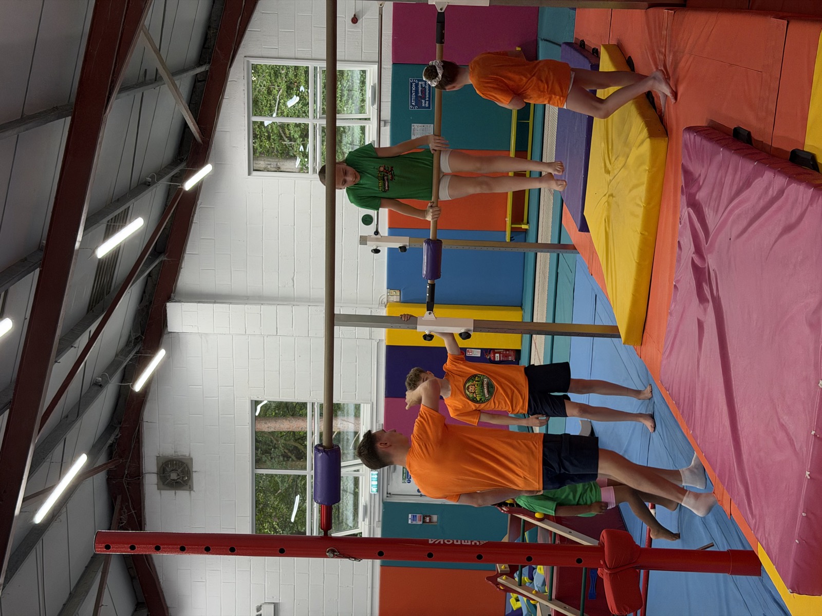 A Jungle Gymnastics coach spotting a young gymnast on the high bar