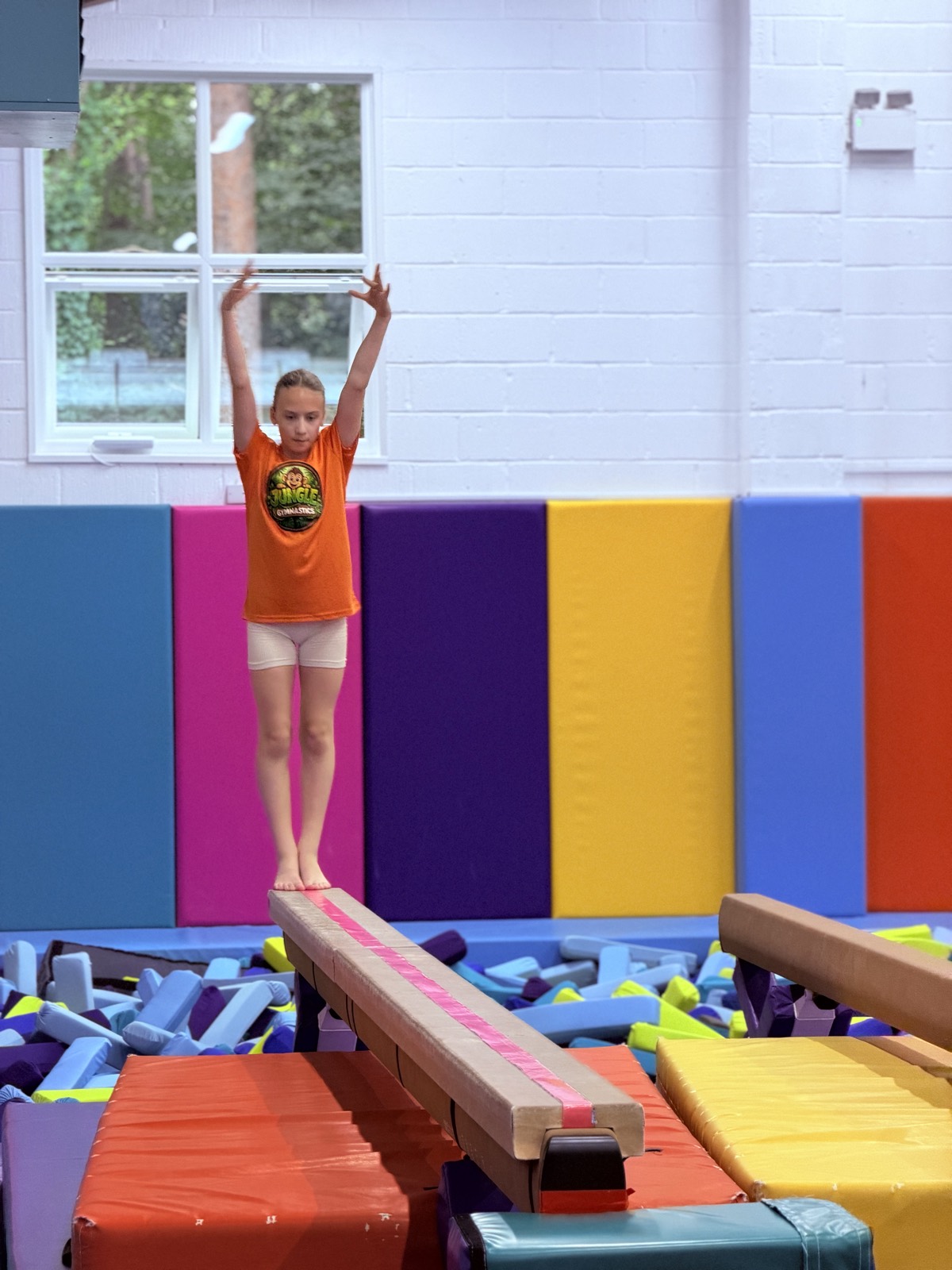 A gymnast finishing on the beam with arms raised