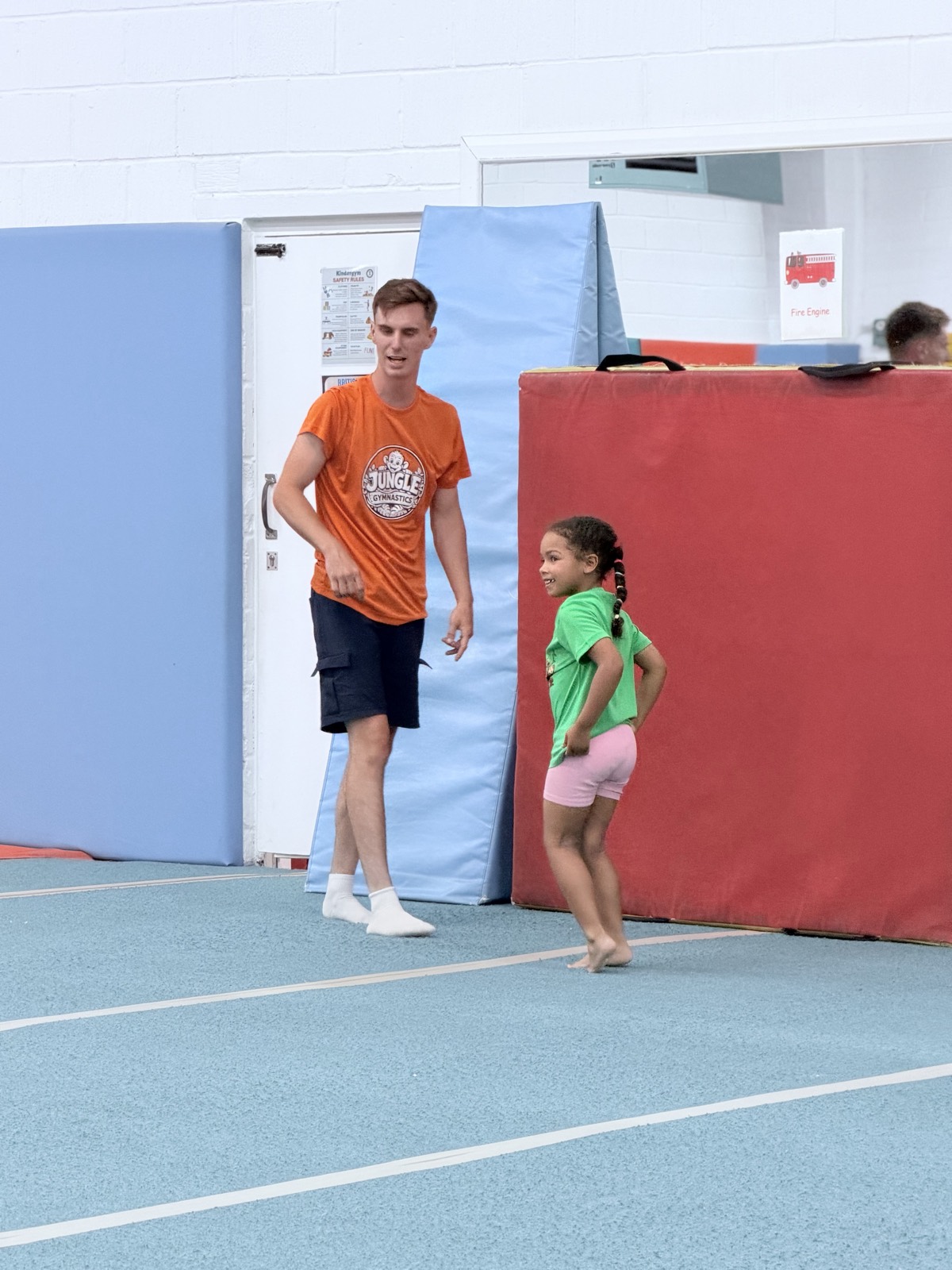 A coach guiding a young gymnast